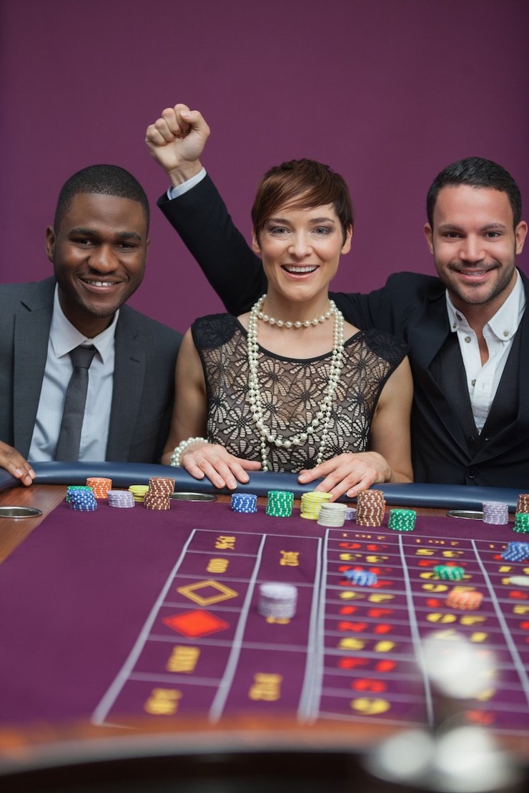 Meja live casino dengan dealer dan para pemain terlibat permainan yang asyik
